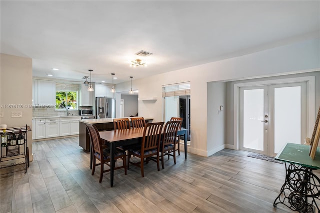 dining area with baseboards, visible vents, light wood-style floors, and french doors