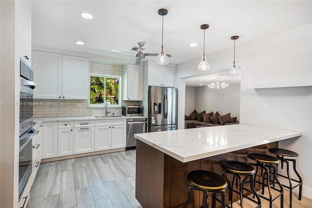 kitchen featuring white cabinets, a breakfast bar, kitchen peninsula, and stainless steel appliances