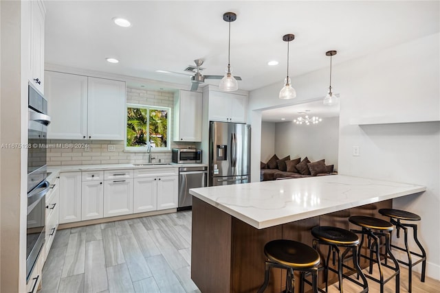 kitchen featuring decorative backsplash, light stone counters, a peninsula, and appliances with stainless steel finishes