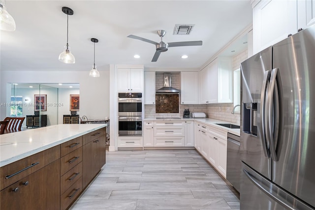 kitchen with white cabinets, wall chimney range hood, sink, and appliances with stainless steel finishes