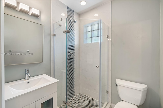 bathroom with vanity, toilet, and a shower with door