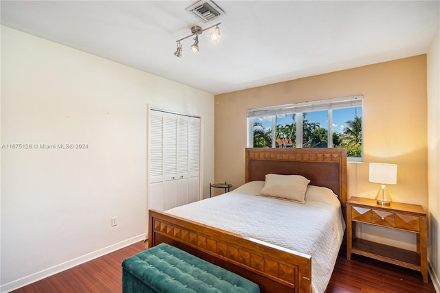 bedroom with baseboards, visible vents, a closet, and wood finished floors