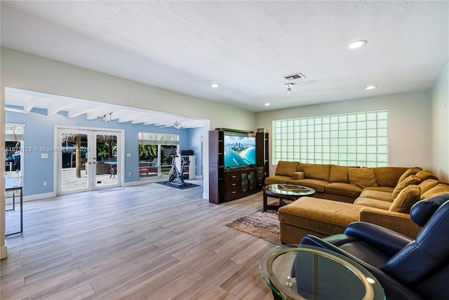 living room featuring ceiling fan, beam ceiling, light wood-type flooring, and french doors