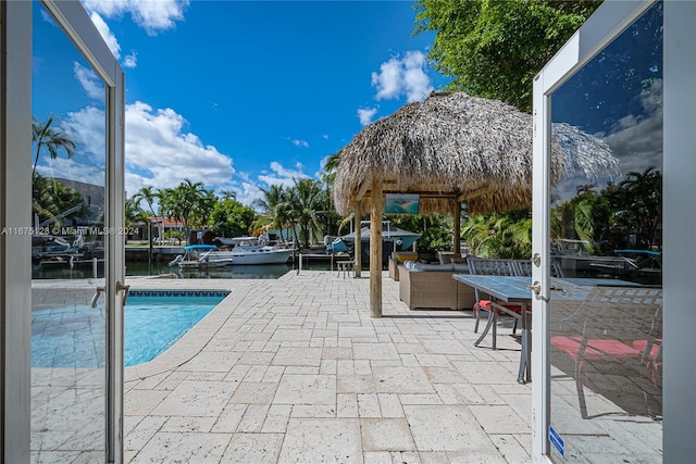 view of pool featuring a patio, a dock, a water view, a gazebo, and outdoor lounge area