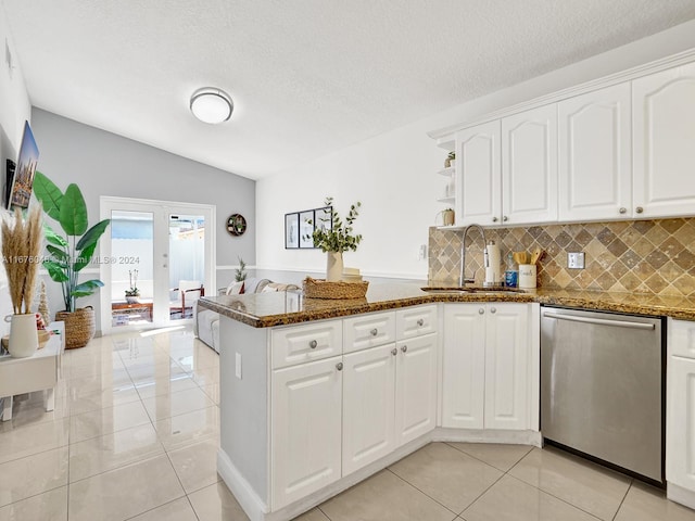 kitchen featuring kitchen peninsula, stainless steel dishwasher, sink, dark stone countertops, and white cabinetry