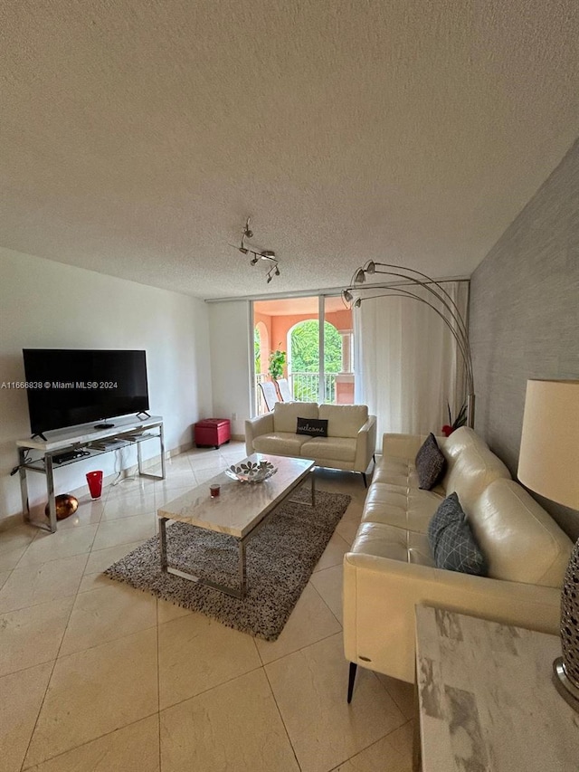 living room with track lighting, tile patterned flooring, and a textured ceiling