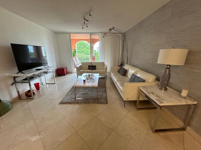 tiled living room featuring rail lighting and a textured ceiling