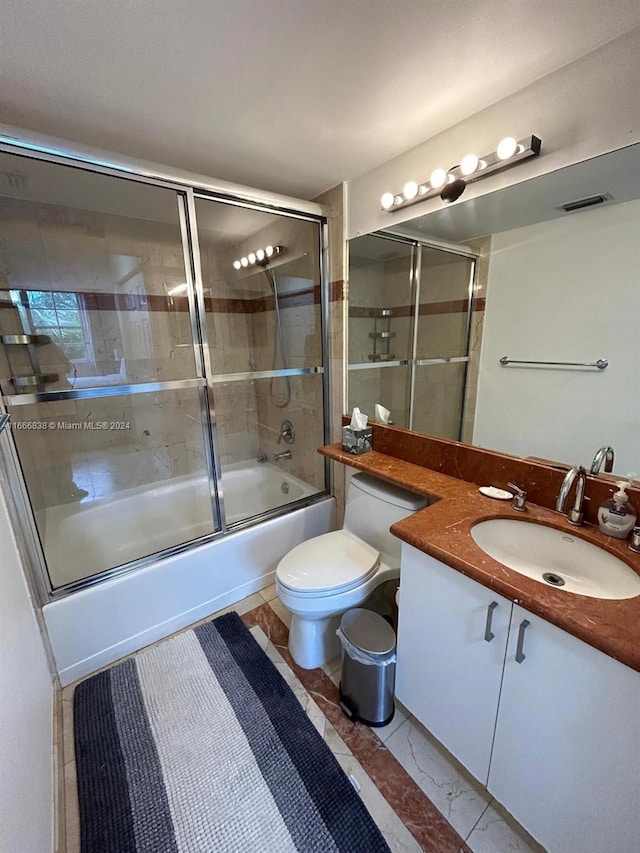 full bathroom featuring enclosed tub / shower combo, vanity, and toilet