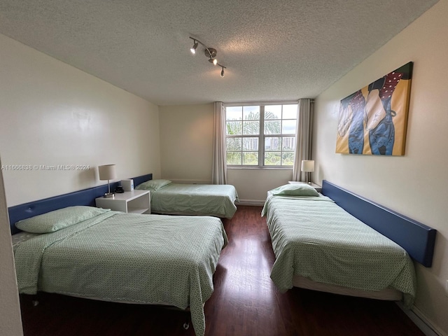 bedroom featuring dark wood-type flooring, rail lighting, and a textured ceiling