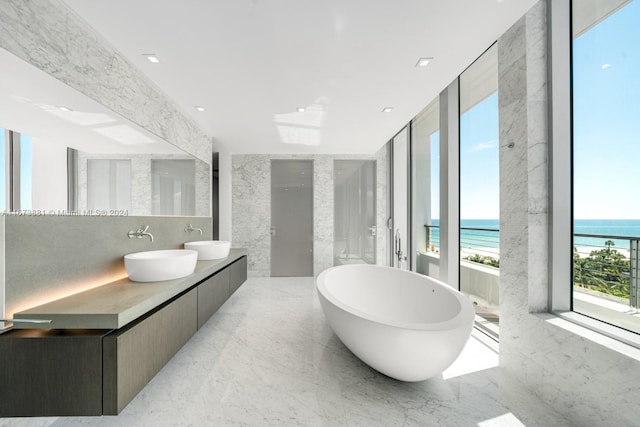 bathroom featuring a tub, a water view, a healthy amount of sunlight, and vanity