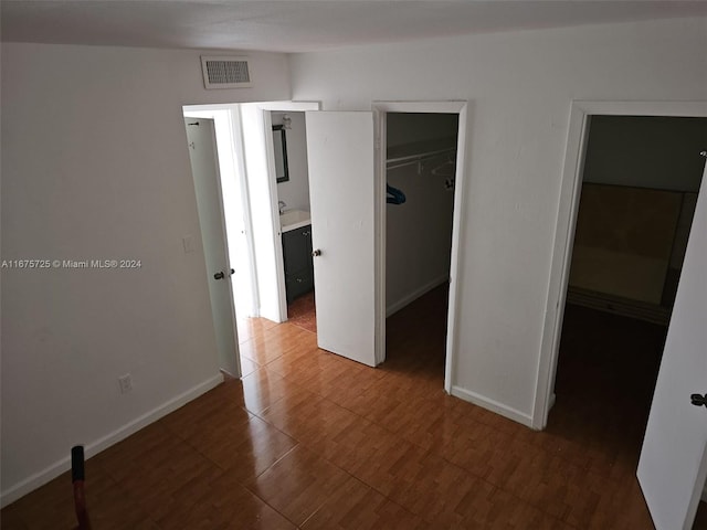 unfurnished bedroom with a walk in closet, baseboards, a closet, and visible vents