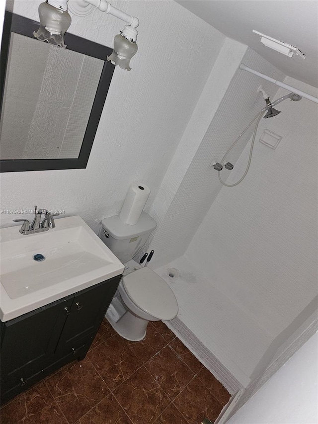 bathroom featuring a shower, tile patterned floors, vanity, and toilet