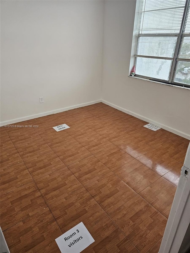 unfurnished room with baseboards, wood finished floors, and visible vents