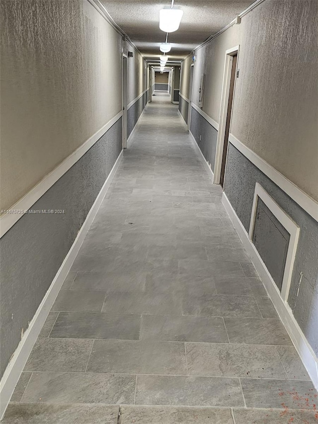 hallway with a textured ceiling and a textured wall