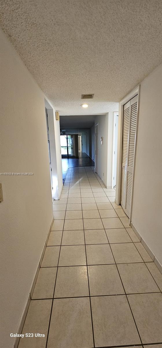 corridor featuring light tile patterned floors and a textured ceiling