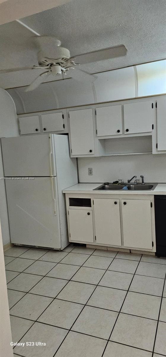 kitchen with a textured ceiling, sink, light tile patterned floors, white fridge, and white cabinetry