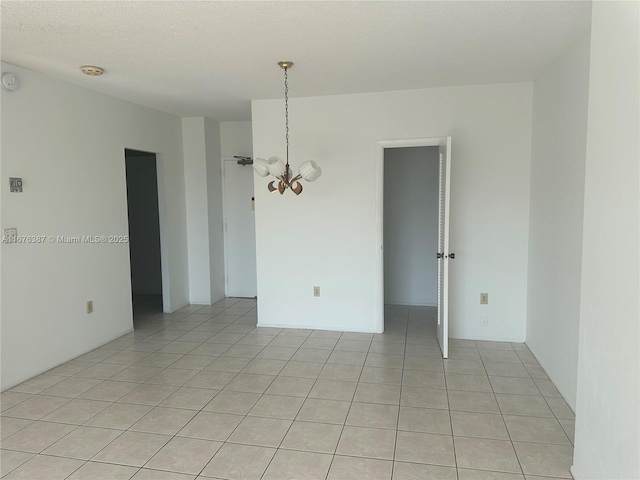 unfurnished room with a textured ceiling, an inviting chandelier, and light tile patterned floors