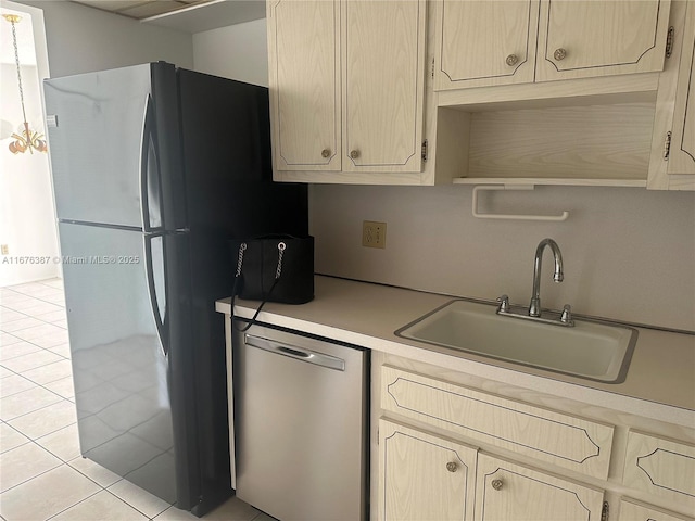 kitchen featuring dishwasher, black fridge, sink, light tile patterned flooring, and light brown cabinets