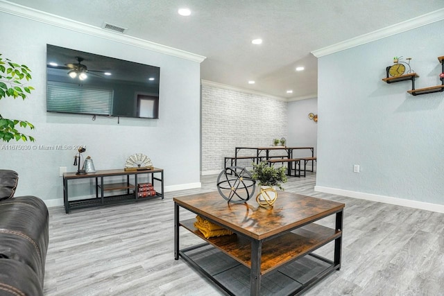 living room with ornamental molding, ceiling fan, and light hardwood / wood-style flooring