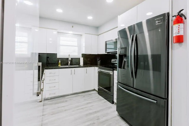 kitchen with tasteful backsplash, white cabinets, sink, light hardwood / wood-style flooring, and appliances with stainless steel finishes