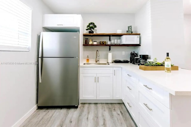 kitchen featuring stainless steel fridge, light hardwood / wood-style flooring, sink, and white cabinets