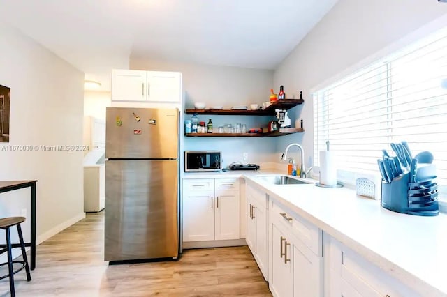 kitchen featuring stainless steel appliances, light hardwood / wood-style floors, sink, and white cabinetry