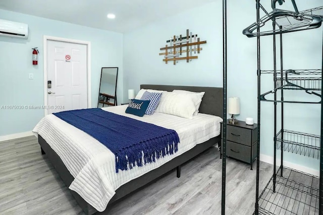 bedroom with a wall unit AC and hardwood / wood-style flooring