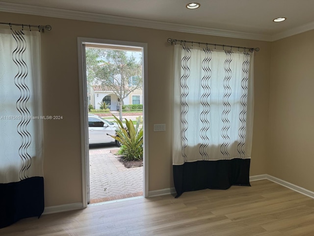 entrance foyer with ornamental molding and light hardwood / wood-style flooring