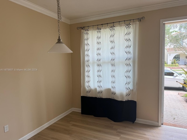 empty room with hardwood / wood-style floors and crown molding