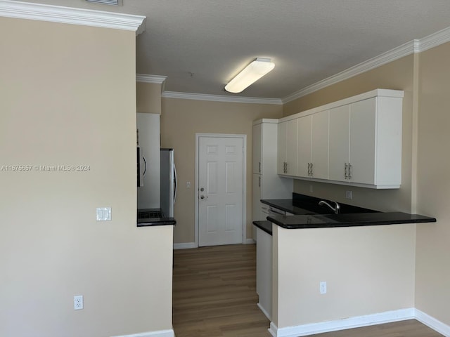 kitchen featuring stainless steel fridge, crown molding, a textured ceiling, light hardwood / wood-style floors, and white cabinets