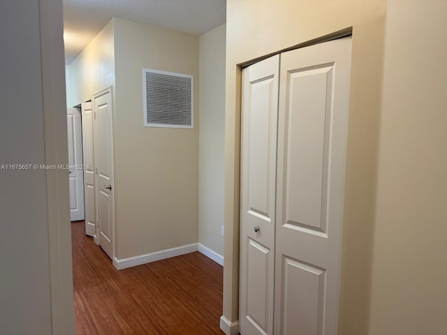 corridor with a textured ceiling and hardwood / wood-style flooring