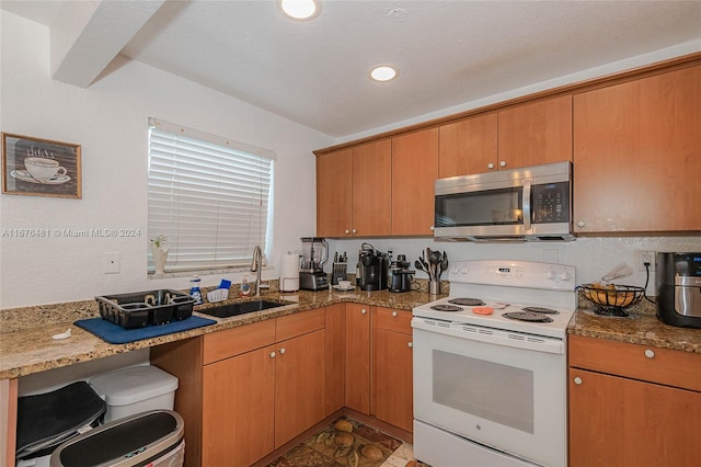 kitchen featuring white electric range, sink, and light stone counters