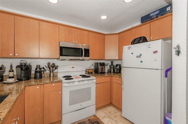 kitchen with a textured ceiling, light stone countertops, and white appliances