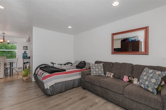 bedroom featuring light hardwood / wood-style floors, a notable chandelier, and a textured ceiling