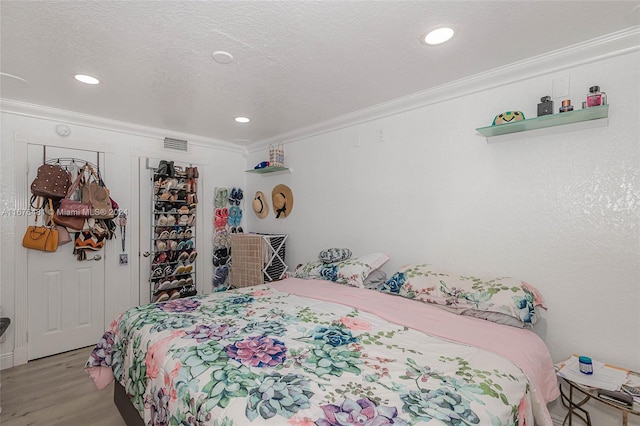 bedroom with crown molding, a textured ceiling, and light wood-type flooring