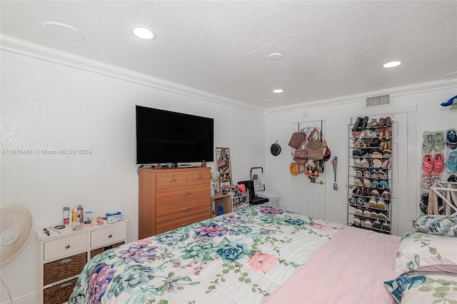 bedroom with ornamental molding, hardwood / wood-style flooring, and a textured ceiling