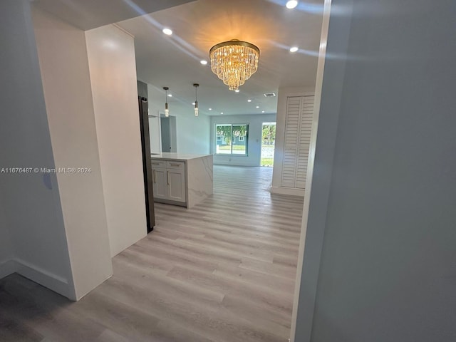 hallway with light hardwood / wood-style floors and a chandelier