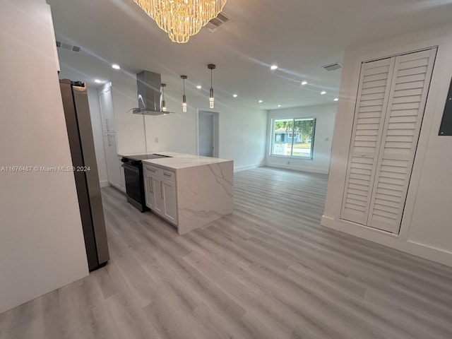 kitchen featuring stainless steel fridge, light wood-type flooring, black electric range oven, white cabinetry, and range hood