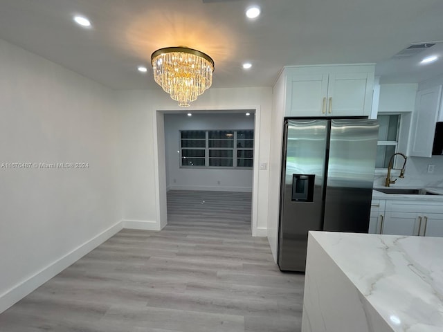 kitchen with white cabinets, sink, stainless steel refrigerator with ice dispenser, light stone countertops, and light wood-type flooring