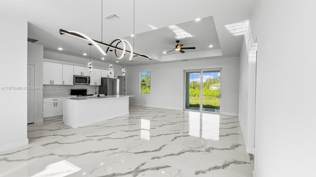 kitchen with sink, stainless steel appliances, an island with sink, pendant lighting, and white cabinets