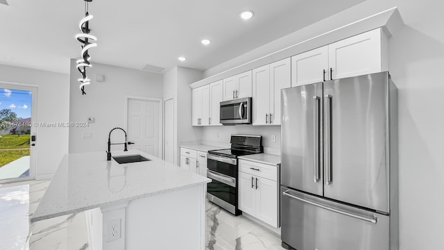 kitchen with a center island with sink, white cabinets, sink, light stone countertops, and stainless steel appliances