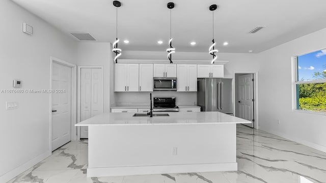 kitchen with stainless steel appliances, white cabinetry, hanging light fixtures, and an island with sink