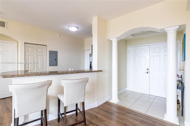 kitchen with electric panel, white cabinetry, kitchen peninsula, a kitchen bar, and hardwood / wood-style flooring