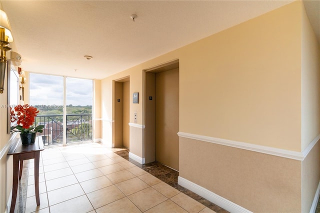 corridor with tile patterned flooring, floor to ceiling windows, elevator, and baseboards