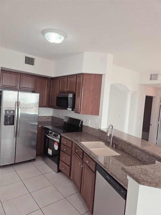 kitchen with a sink, visible vents, appliances with stainless steel finishes, and dark stone counters