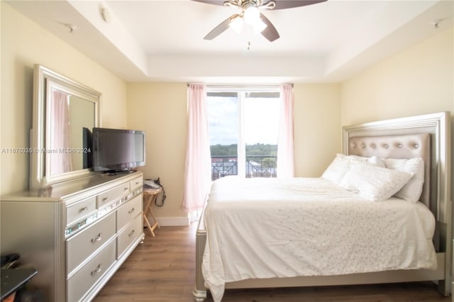 bedroom with dark hardwood / wood-style floors, a tray ceiling, and ceiling fan