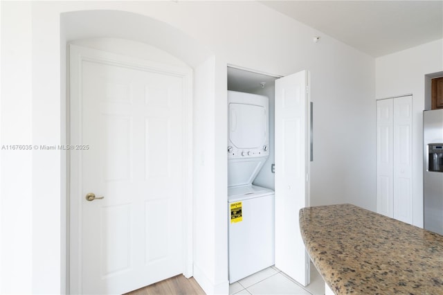 washroom featuring laundry area, light tile patterned floors, and stacked washer and clothes dryer