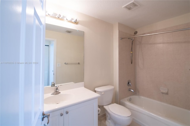 full bathroom featuring tiled shower / bath, vanity, and toilet