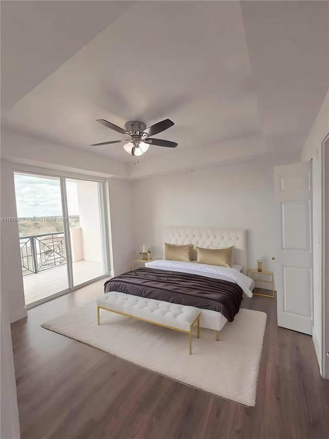 bedroom with a ceiling fan, access to exterior, dark wood-style floors, and a raised ceiling