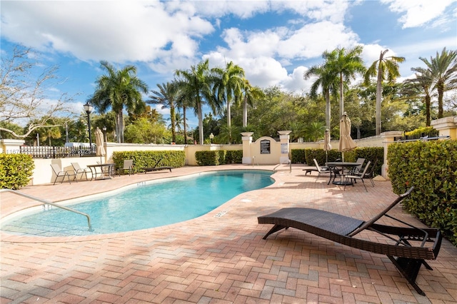 community pool with a patio area and fence